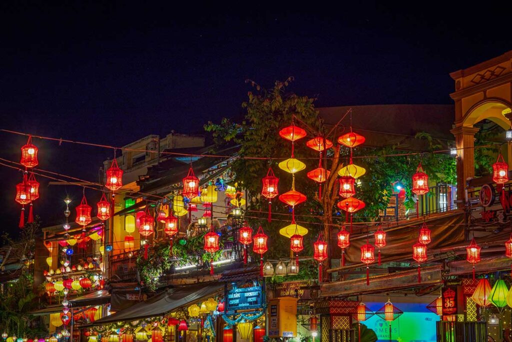 Red and yellow lanterns lighting up a lively street in Hoi An Ancient Town at night, creating the town’s signature magical evening atmosphere.