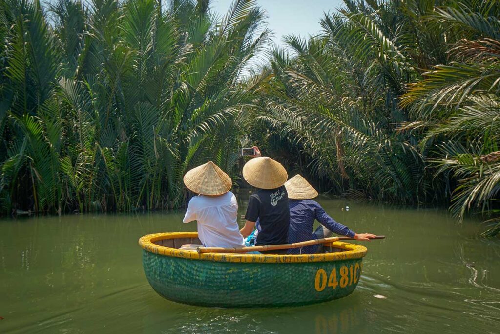 Travelers taking a traditional basket boat ride through the coconut palms – iconic activity in the Hoi An countryside.