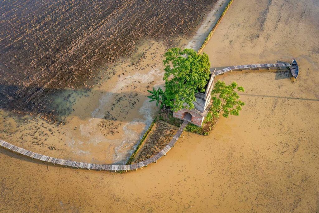 Aerial view of Duy Phuoc with flooded fields around a old kiln tower – unique rural landscape in the Hoi An countryside.