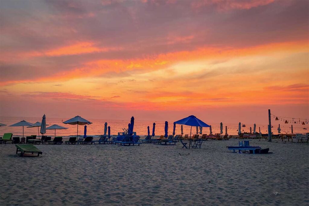 Hoi An Hidden Beach sunset with umbrellas – Fiery sunset over Hoi An’s Hidden Beach, with beach umbrellas and loungers silhouetted against the colorful sky.