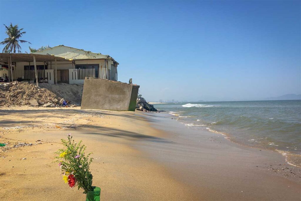 Hoi An Hidden Beach erosion damage – A seaside house at Hidden Beach, Hoi An, showing coastal erosion where waves reach the base of the building.