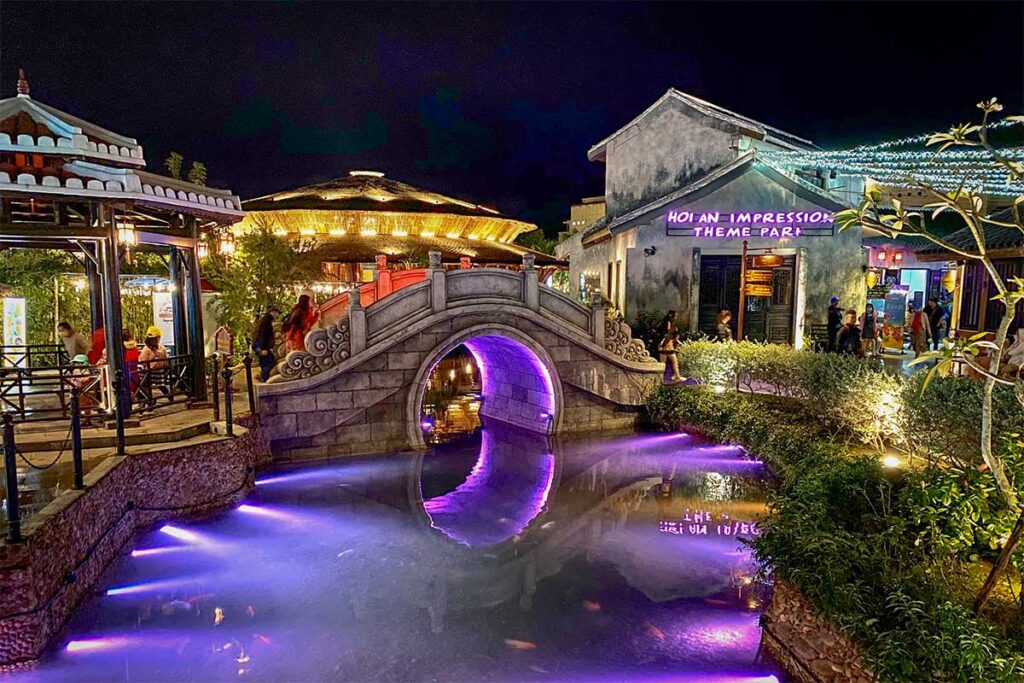 Bridge and canal lit up with purple lights at Hoi An Impression Theme Park.