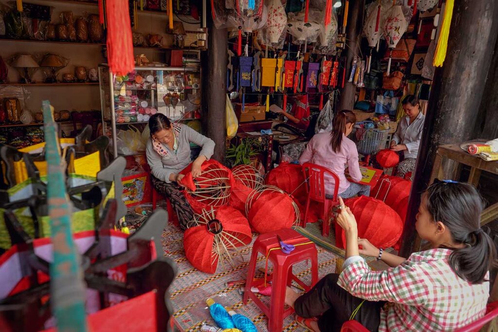 Group of lantern makers working together in Hoi An, teaching visitors the art of lantern making.