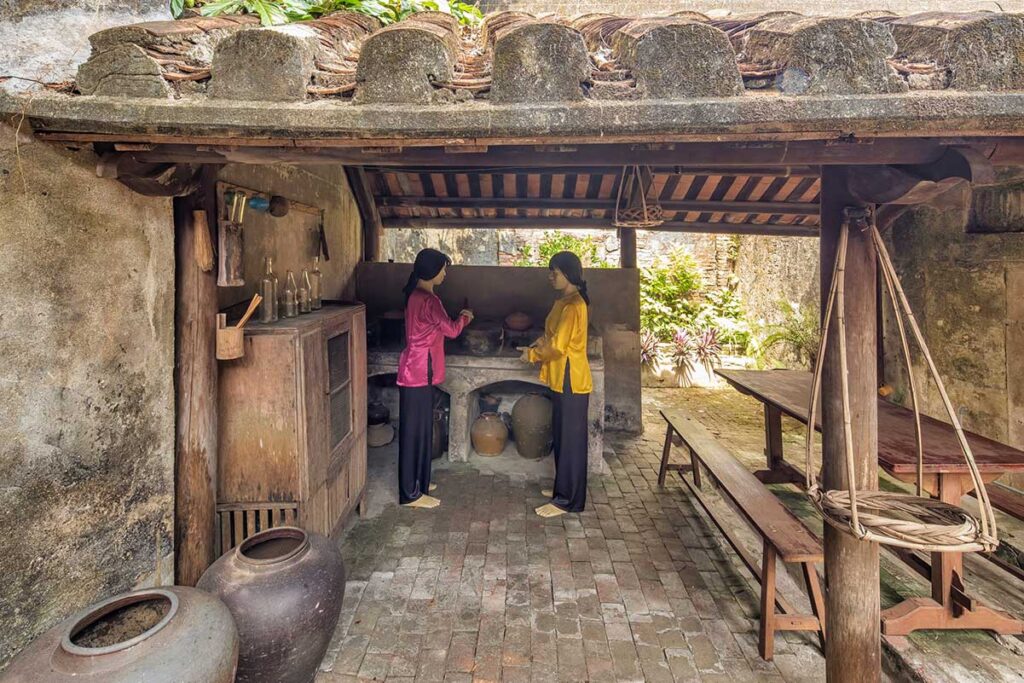 Recreated traditional kitchen at Hoi An Museum of Trade Ceramics with mannequins in silk áo dài – illustrating daily life and cooking practices in historic Vietnamese homes.