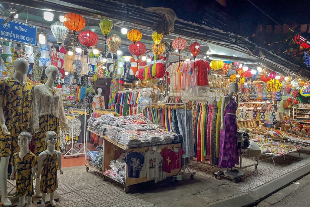 Clothing and souvenir stalls with lanterns, dresses, and handmade bags at Hoi An Night Market.