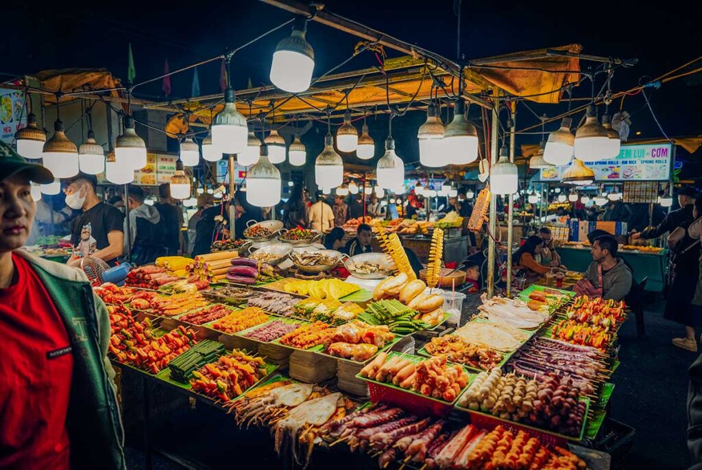 Grilled skewers, seafood, and local street food displayed under bright lamps at Hoi An Night Market.