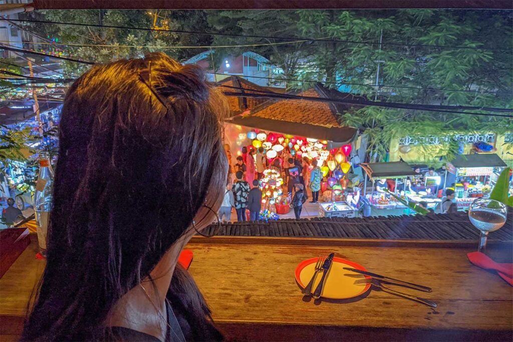 Traveler enjoying the lantern-lit view of Hoi An Night Market from a rooftop restaurant at nigh