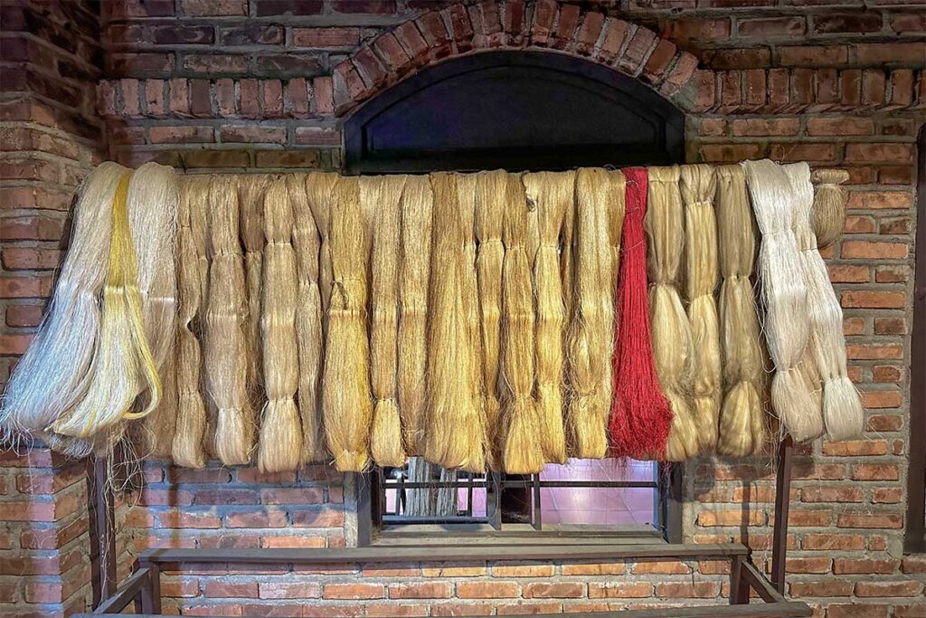 Natural silk threads in various shades hanging to dry inside Hoi An Silk Village.