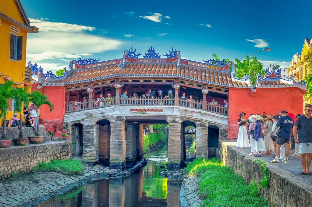 The iconic Japanese Covered Bridge in Hoi An Ancient Town, a 16th-century landmark with ornate wooden architecture and tiled roof crossing a small canal.