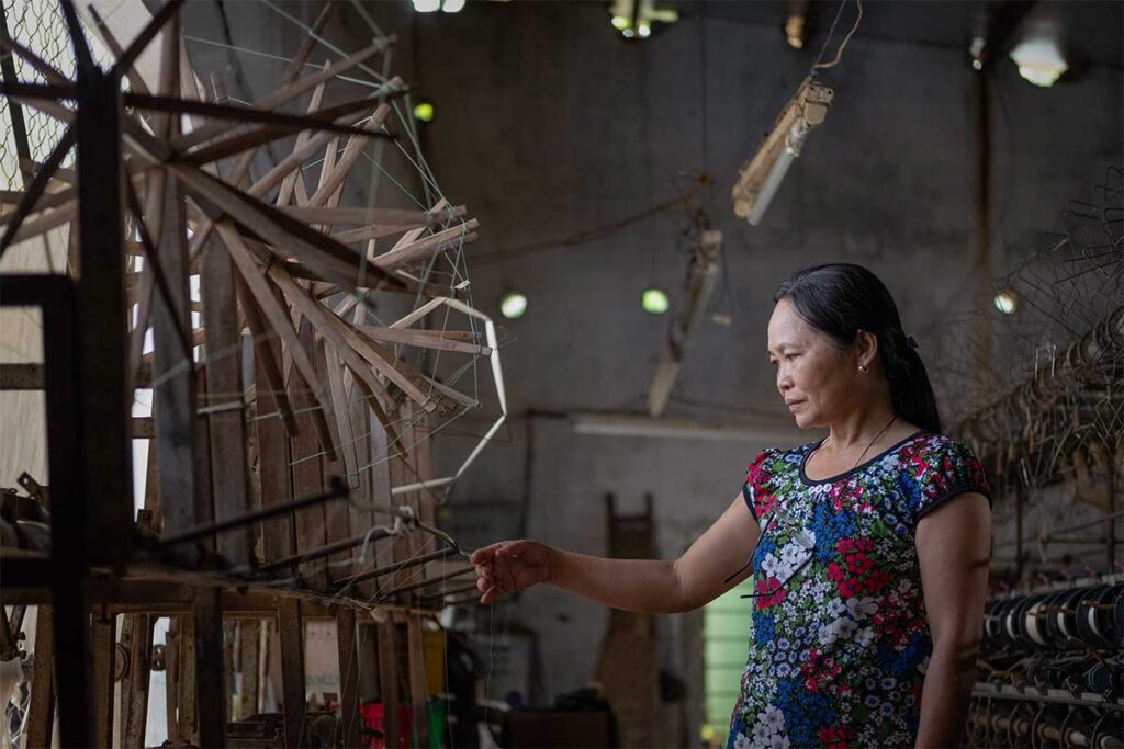 Vietnamese woman working with traditional silk reeling equipment at Ma Chau Silk Village near Hoi An.