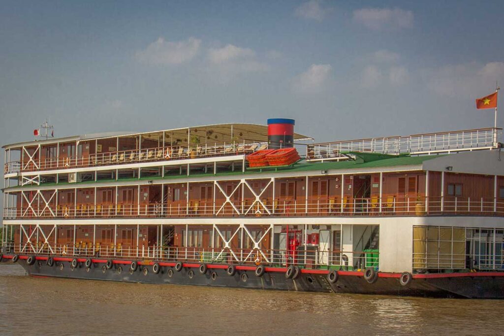 Traditional three-deck Mekong Delta cruise vessel on the river with Vietnamese flag