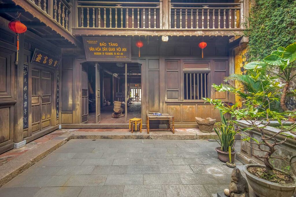 Courtyard entrance to the Hoi An Folklore museum inside a preserved wooden merchant house, with lanterns and potted plant
