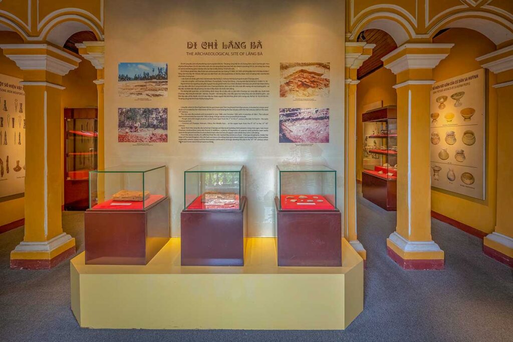 Museum of Sa Huynh Culture Hoi An interior with archaeological displays – Glass cases showcasing ancient Sa Huynh artifacts with detailed panels explaining excavation findings at Lang Ba site.
