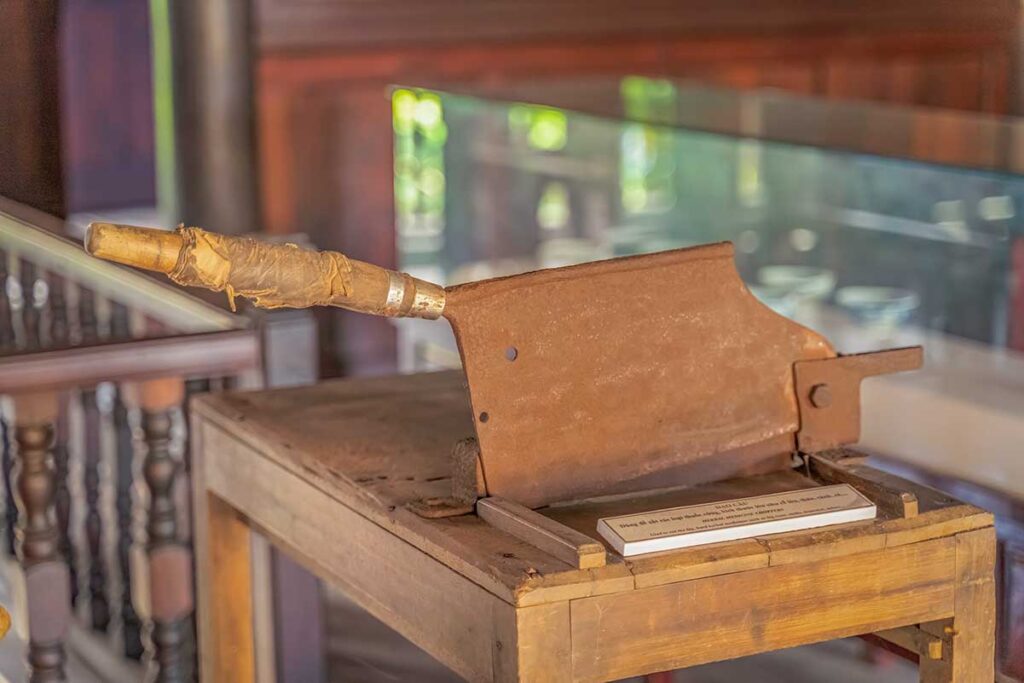 Rustic traditional cleaver on a wooden stand, once used for preparing herbal medicine, on display at the Museum of Traditional Medicine in Hoi An.