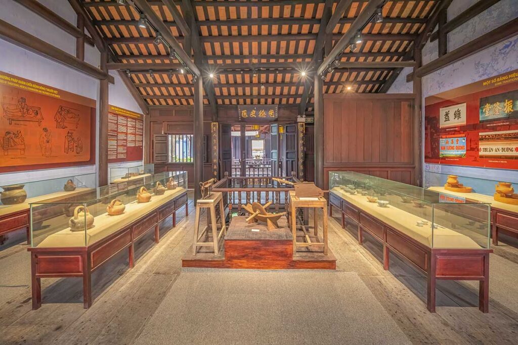 Interior of the Museum of Traditional Medicine in Hoi An with wooden beams, display cases of ancient medical tools, and panels describing healing methods