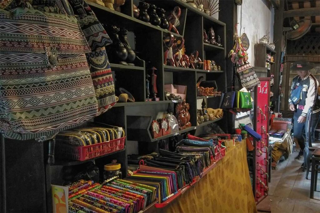 Display of local handicrafts and souvenirs inside Phung Hung Old House, with colorful bags, wooden carvings, and traditional textile products.
