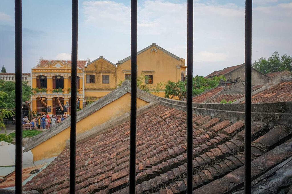 View from Phung Hung Old House across the tiled rooftops of Hoi An Ancient Town, highlighting yellow heritage buildings and old architecture.