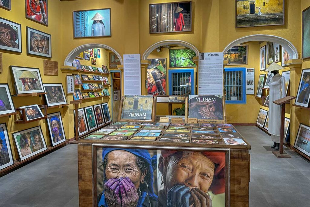 Photography gallery inside Precious Heritage Museum Hoi An – Collection of framed portraits, books, and photo prints capturing Vietnamese culture.