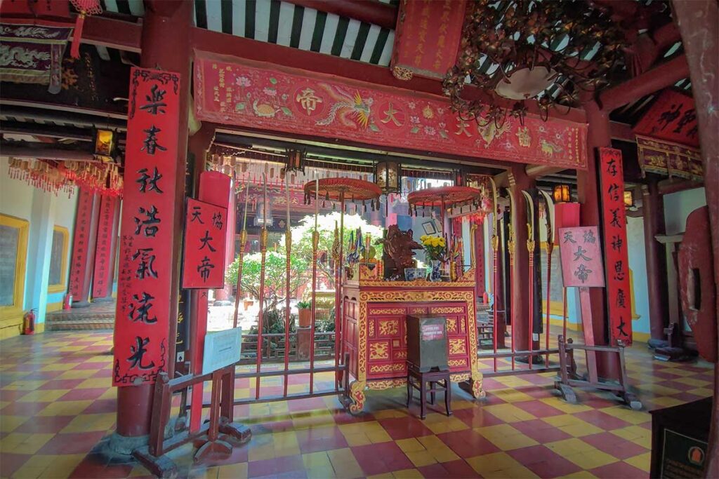 Main ceremonial hall of Quan Cong Temple with red pillars and golden details