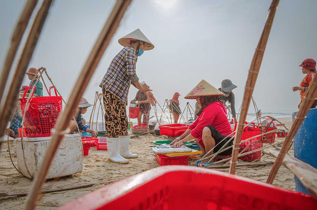 Women sorting and weighing seafood at Tam Tien Fish Market in Quang Nam.