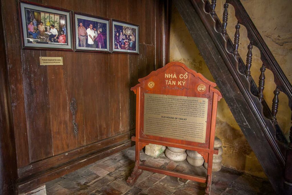 Historical information panel and family photographs displayed near the staircase inside Tan Ky Old House in Hoi An