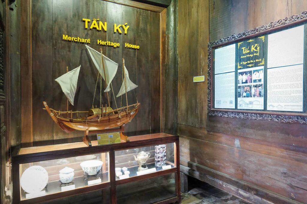 Exhibit at Tan Ky Old House, showcasing a traditional wooden boat model and antique ceramics that highlight Hoi An’s trading past.