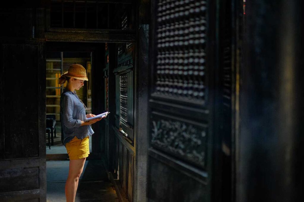 Visitor exploring the dimly lit wooden interior of Tan Ky Old House, a preserved 18th-century merchant residence in Hoi An.