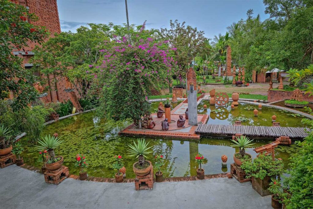 Scenic pond with terracotta statues and brick pathways at Thanh Ha Terracotta Park in Hoi An