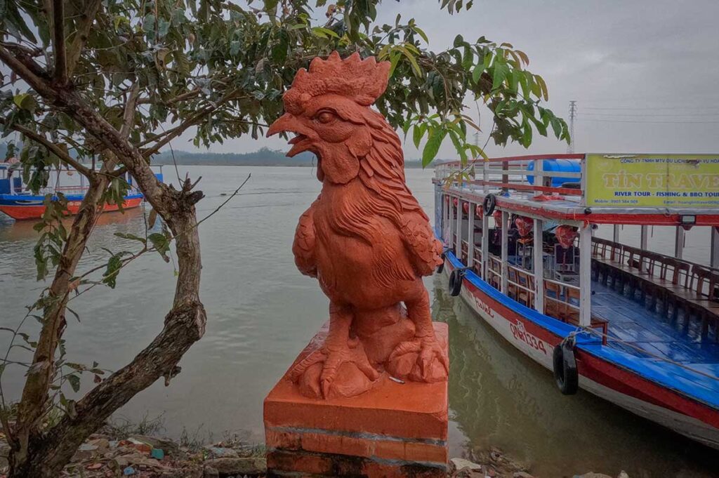 Clay rooster statue by Thu Bon River Hoi An – Iconic terracotta rooster sculpture standing near the boat pier at Thanh Ha village.