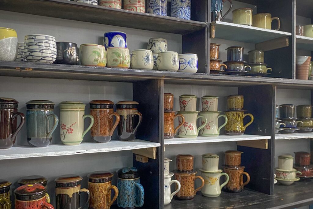 Thanh Ha Pottery Village souvenir shop – shelves of traditional Vietnamese ceramic cups and mugs on display, showcasing local craftsmanship near Hoi An.