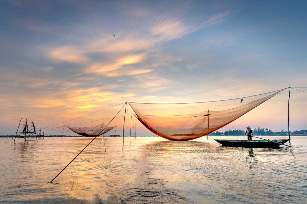 Traditional fishing boats with red flags on the Thu Bon River – scenic stop on a cultural boat ride in Hoi An.