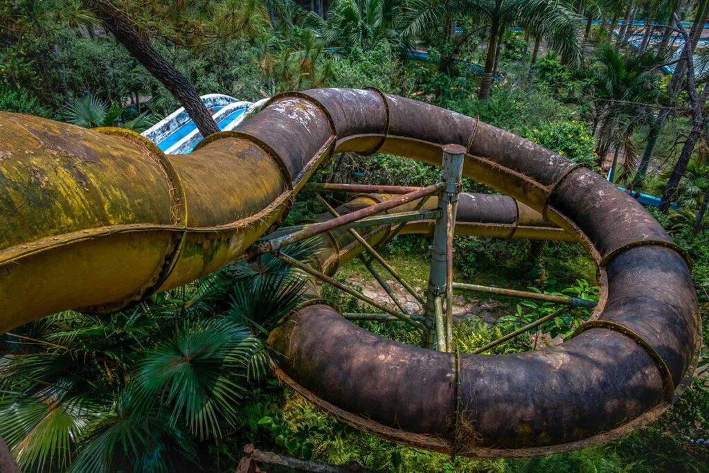 Waterslides covered in moss and dirt inside Thuy Tien abandoned water park in Hue