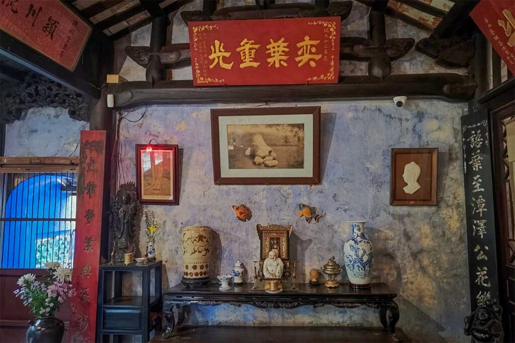 Detailed view of antique altar table with blue and white ceramics and statues inside Tran Family Chapel, Hoi An.