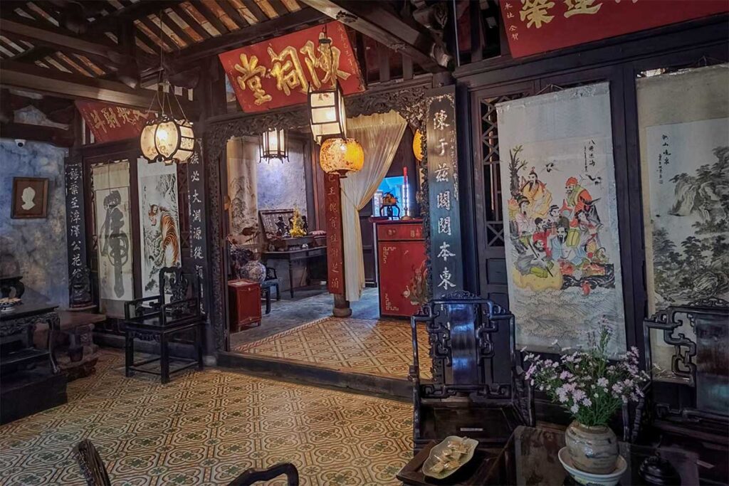 Intricately carved wooden chairs and traditional artwork in the main living hall of Tran Family Chapel, Hoi An.