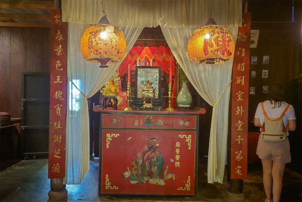 Wooden ancestral shrine with red lacquer details and ceremonial objects at Tran Family Chapel, central Vietnam.