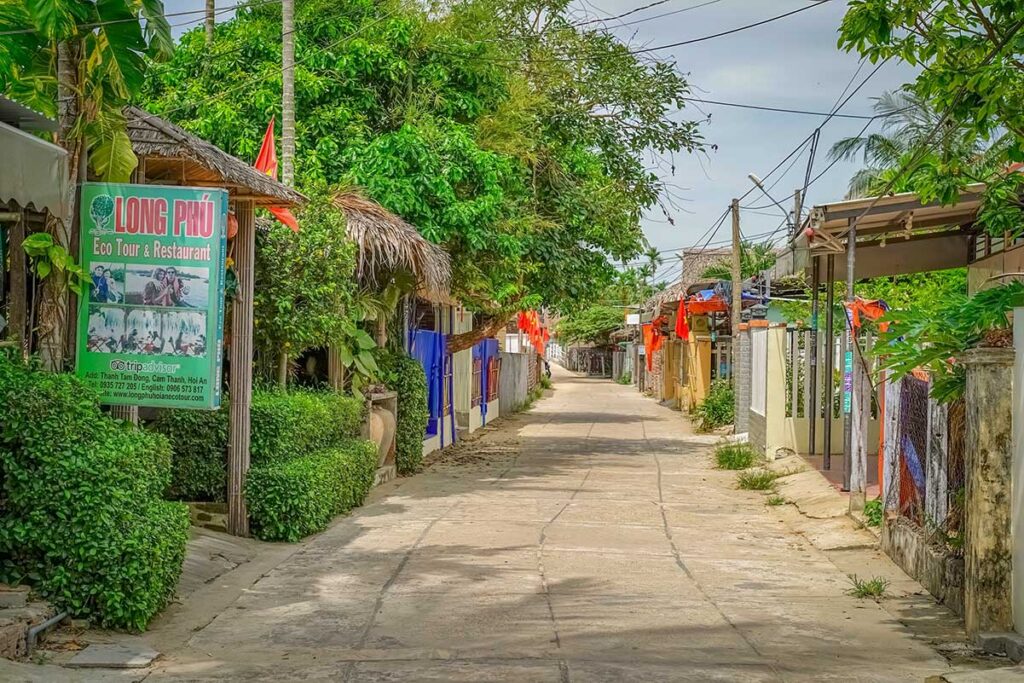 Small lane in Cam Thanh Village with eco-tour signs and local houses.