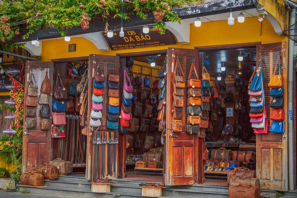 Exterior of a leather shop in Hoi An Ancient Town with handbags, belts, and travel bags on display.
