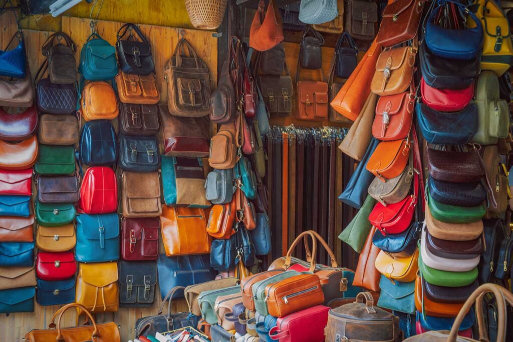 Leather bags in multiple colors and styles hanging in a traditional Hoi An leather workshop shop.