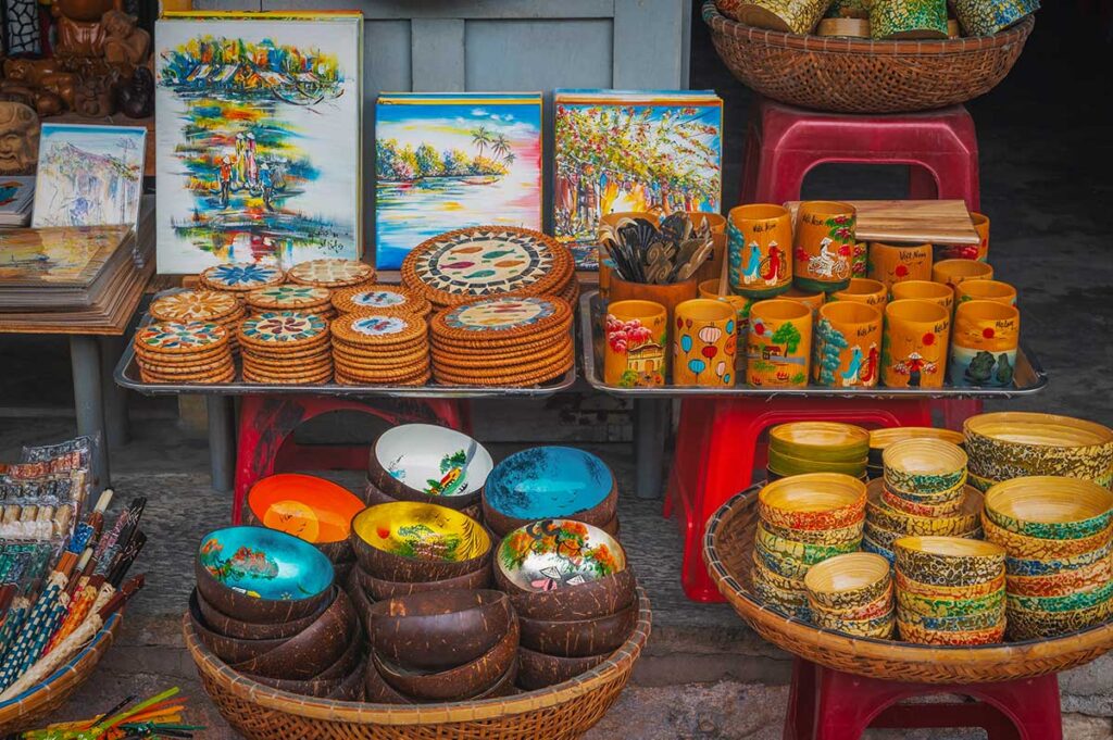 Bamboo and coconut shell handicrafts for sale in a Hoi An souvenir shop, including bowls, cups, and paintings.