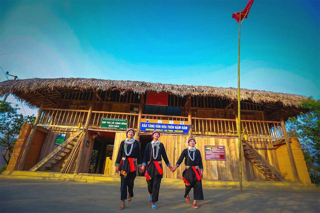 Three local Red Dao ethnic woman are standing in front of their homestay in Nam Dam Village