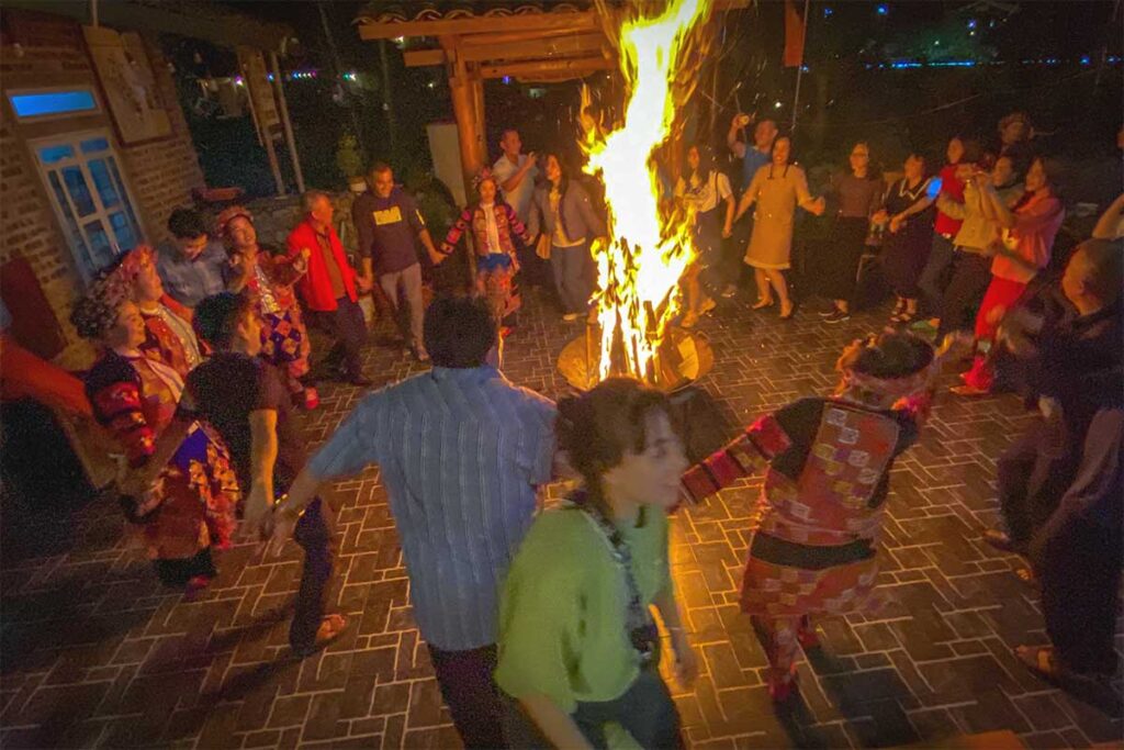 People dance around a campfire at a homestay in Pa Vi Village