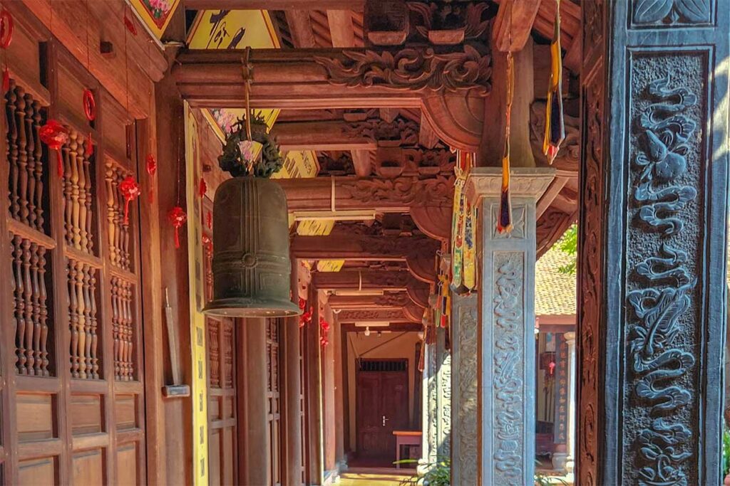 A bronze bell hanging in the outdoor hallway of Boc Pagoda