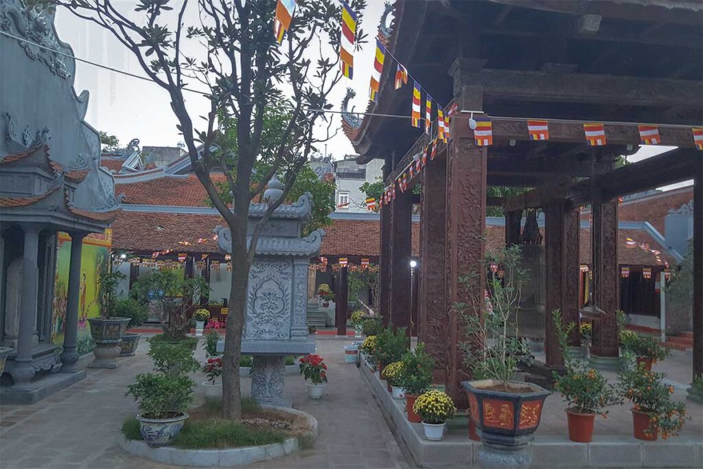 The interior outside space within Hai Ba Trung Temple with a small temple building and a shrine