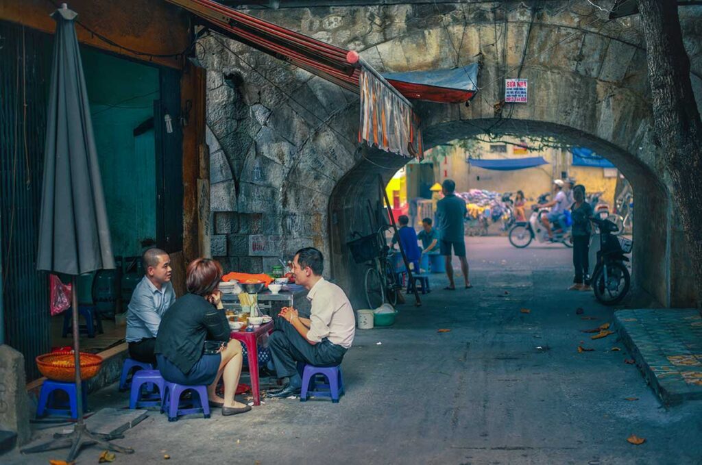 Local people of Hanoi eating Pho at a street food stall near Hanoi Old City Gate