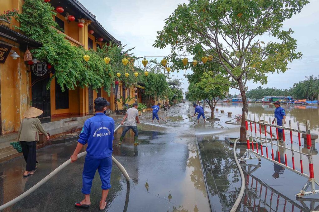 Locals cleaning the street from mud after flooding in Hoi An