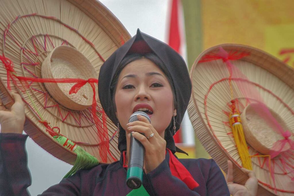 A woman wearing traditional clothes is doing a Quan Ho Singing Performance during the Lim Festival in Bac Ninh