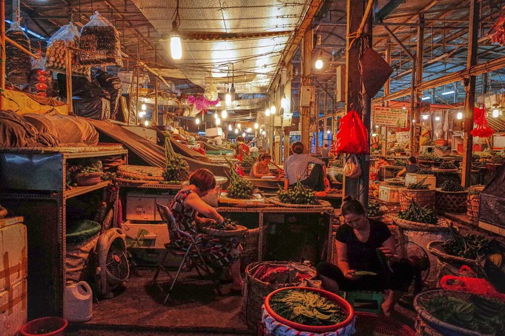 Locals sitting at wholesale market stalls deep at night at the Long Bien Market in Hanoi