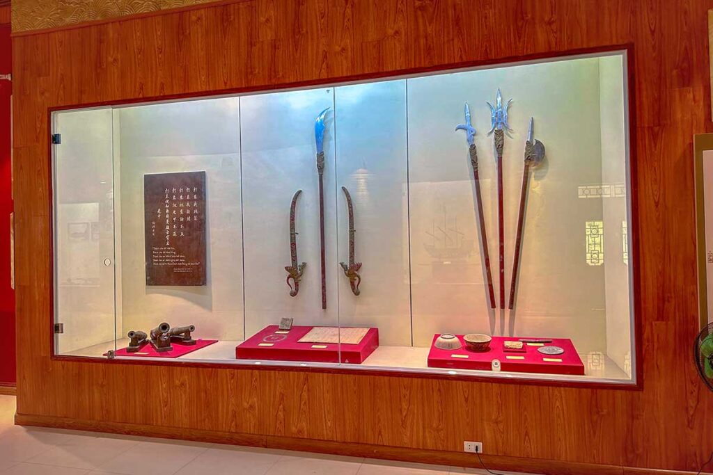 Exhibition case at Quang Trung Museum showcasing swords, spears, and documents from the Tay Son period.