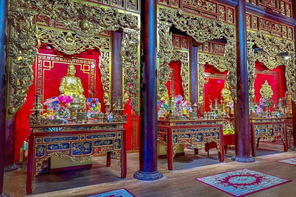Ornate altar hall inside Tay Son Tam Kiet Temple at Quang Trung Museum, with golden statues and richly decorated carvings honoring the Tay Son brothers and their generals.