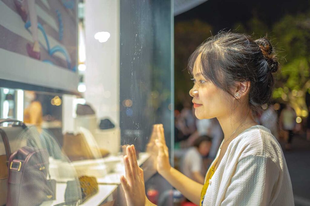 An Asian girl looking through the windows of a fashion store while shopping in Hanoi